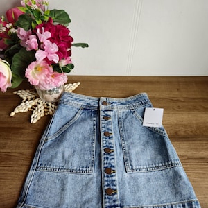 May include: A light blue denim skirt with a button front closure and two front pockets. The skirt has a slightly A-line shape and is made of a soft, comfortable fabric.