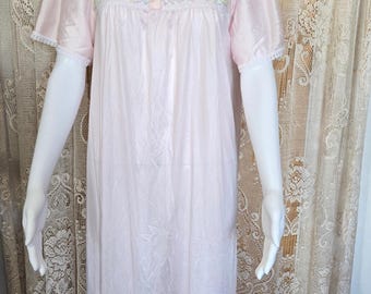 Könnte beinhalten: Ein hellrosa Vintage-Nachthemd mit kurzen Ärmeln und einem quadratischen Ausschnitt. Das Oberteil hat Spitzen- und Banddetails mit drei kleinen Knöpfen. Das Nachthemd wird auf einer Schaufensterpuppe präsentiert.
