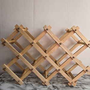 Peut inclure: Un porte-bouteilles en bois avec un design en croisillon. Le porte-bouteilles est en bois brun clair et a une finition naturelle. Il peut contenir jusqu'à 12 bouteilles de vin.