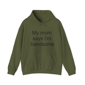 Puede incluir: Una sudadera con capucha verde con el texto "My mom says I'm handsome" impreso en la parte delantera.
