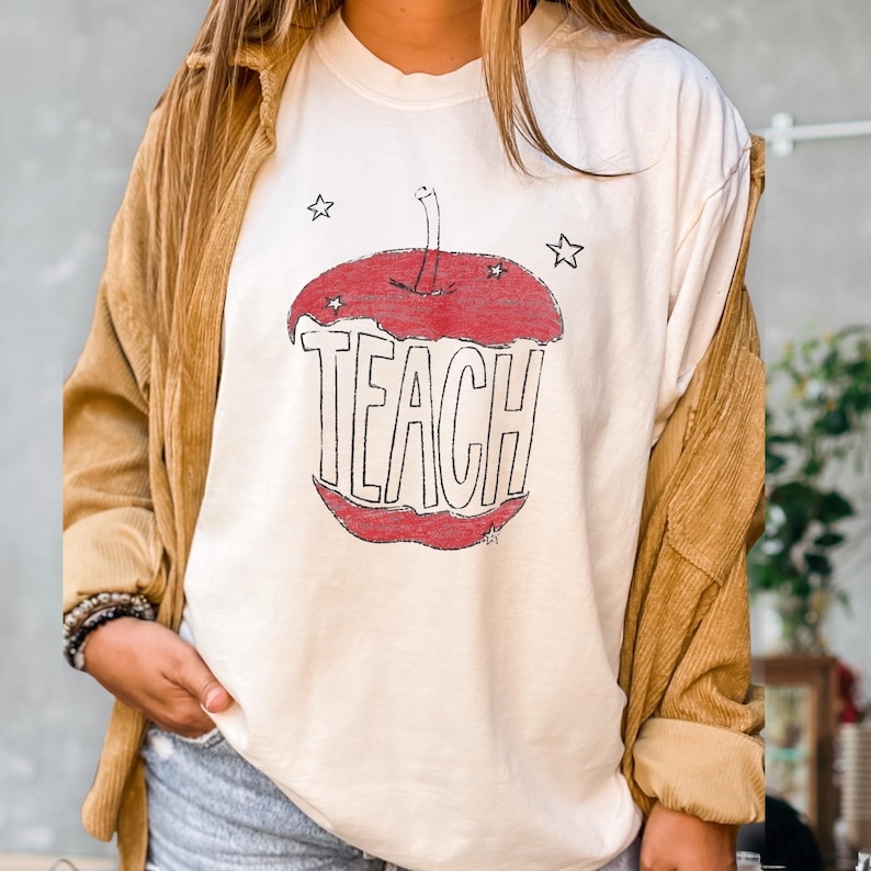 Hand drawn TEACH apple shirt for teachers on ivory tee, vintage childlike apple sketch with imperfect pencil lines and red crayon texture, Free People inspired teacher style