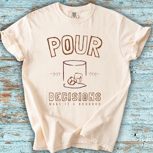For the bourbon lovers! POUR DECISIONS (make it a bourbon) with a simple distressed line drawing of a whiskey glass with two ice-cubes. Brown graphics on ivory.