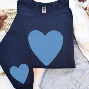 Navy crewneck sweatshirt featuring a large Carolina blue heart on the chest and a smaller matching Carolina blue heart on the right sleeve.