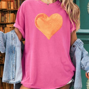 Comfort Colors pink t-shirt with watercolor orange heart design in blossom and crunchberry pink.
