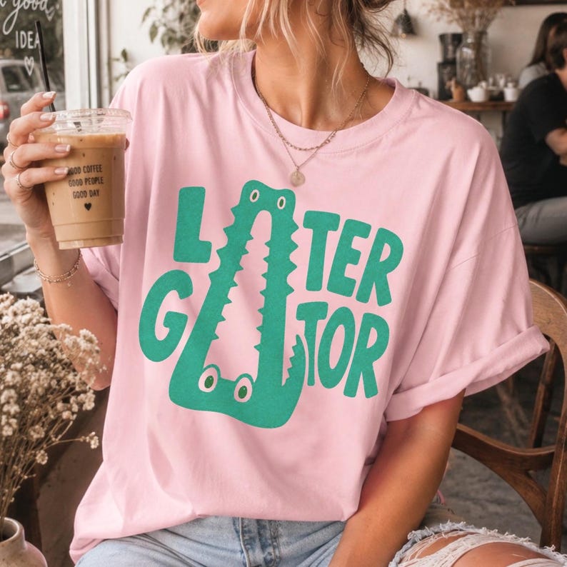 LIGHT PINK Comfort Colors graphic tee featuring a playful Later Gator alligator illustration forming the letter A in chunky retro green typography.