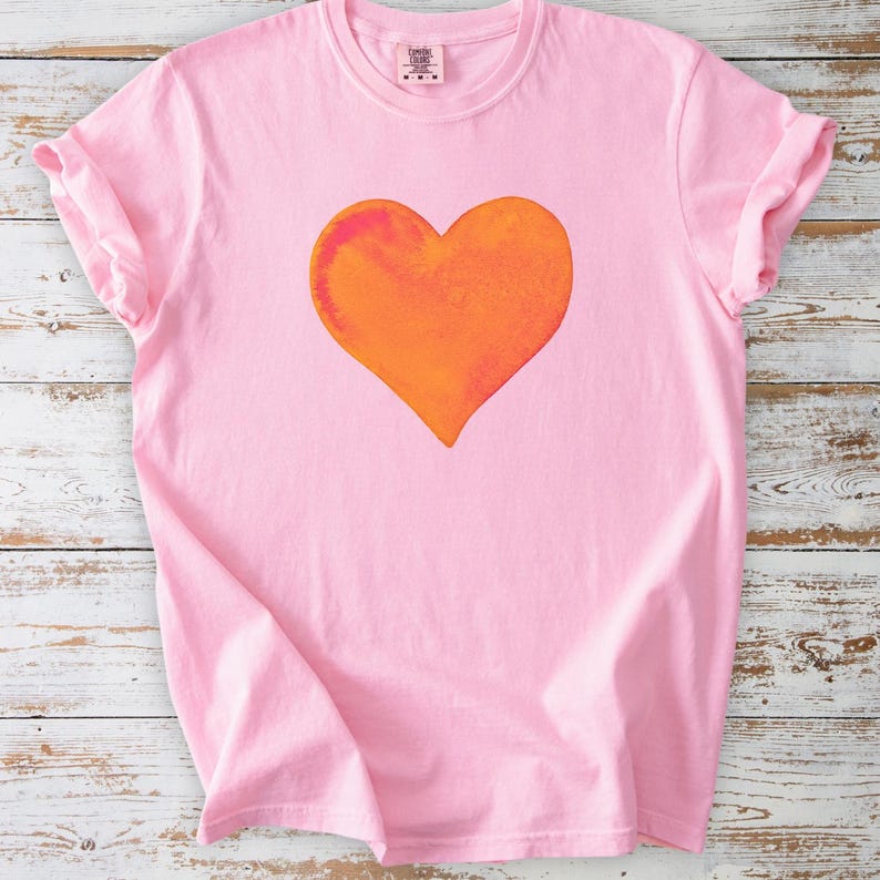 Comfort Colors pink t-shirt with watercolor orange heart design in blossom and crunchberry pink.