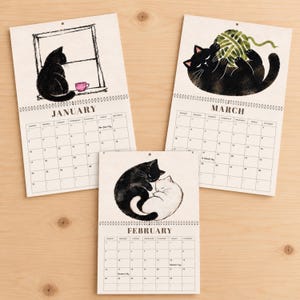 Black cat 2027 wall calendar showing January February and March pages with original watercolor cat illustrations