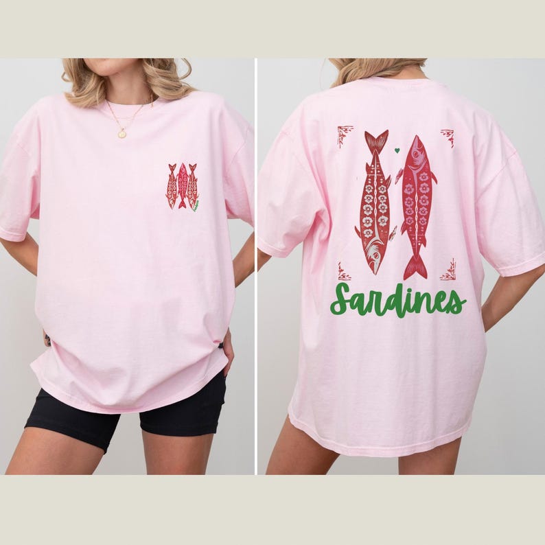 Distressed oversized graphic tee with a vintage fisherman aesthetic. Small red sardines graphic on the front chest, full-size distressed red sardines print on the back with sardines in green script. Nautical, retro inspired design with a worn-in look