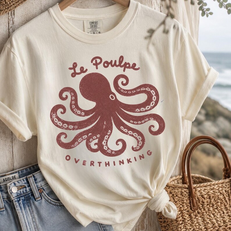 Ivory Comfort Colors octopus graphic shirt flat lay with denim and straw tote.