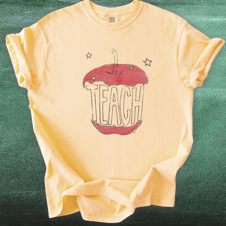 Aesthetic teacher shirt in butter yellow featuring hand drawn apple with TEACH lettering, vintage sketch style teacher tee inspired by Anthropologie