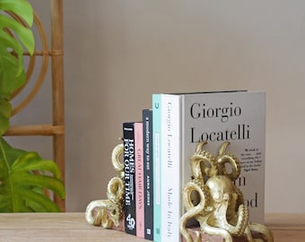May include: A pair of gold-colored octopus bookends with textured tentacles and heads, each mounted on a rectangular wooden base, supporting a row of five books with various titles including Giorgio Locatelli and Great Hair Days.