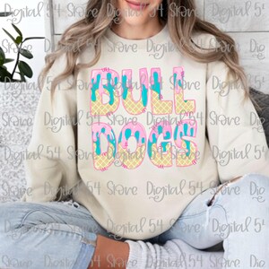Op de afbeelding: Een crèmekleurige sweatshirt met de tekst "BULL DOGS" in een kleurrijk, speels ontwerp. De letters zijn gestileerd als ijsjes met roze, blauwe en gele accenten. Een leuke en casual top.