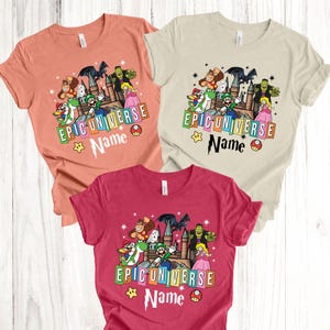 May include: Three short-sleeved t-shirts in peach, beige, and red. Each shirt features a colorful graphic with cartoon characters, a castle, and the text "EPIC UNIVERSE" and "Name". A star and mushroom are also included.