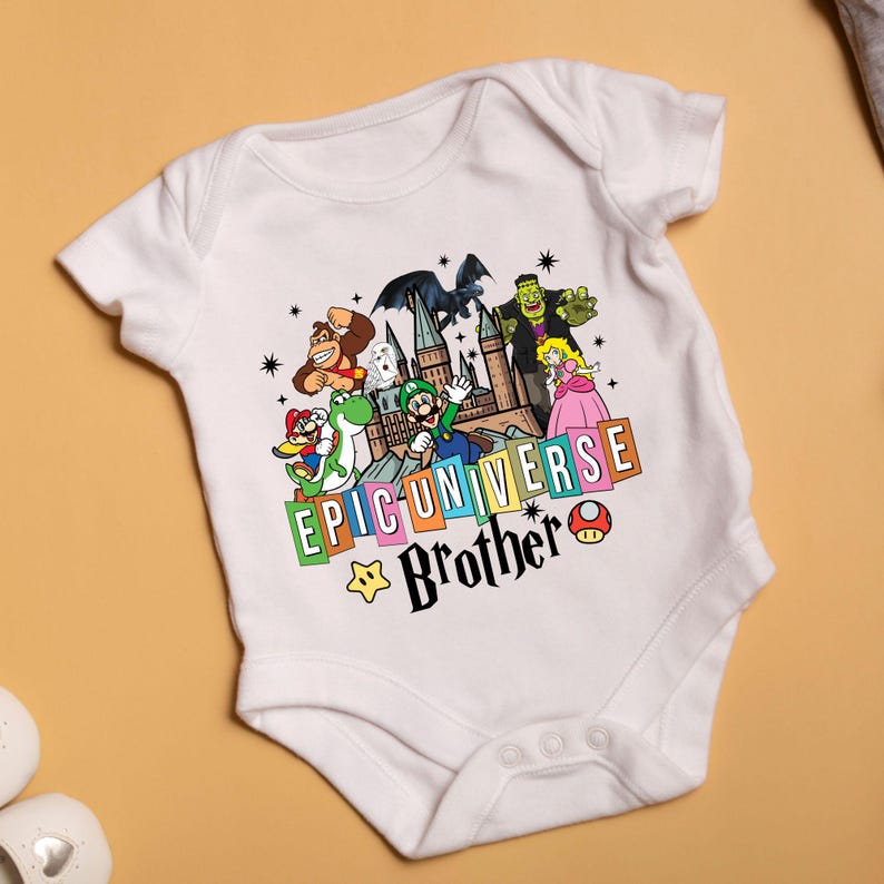 May include: White baby bodysuit with a colorful graphic featuring cartoon characters and the text "EPIC UNIVERSE Brother". The design includes a castle, stars, and a mushroom.
