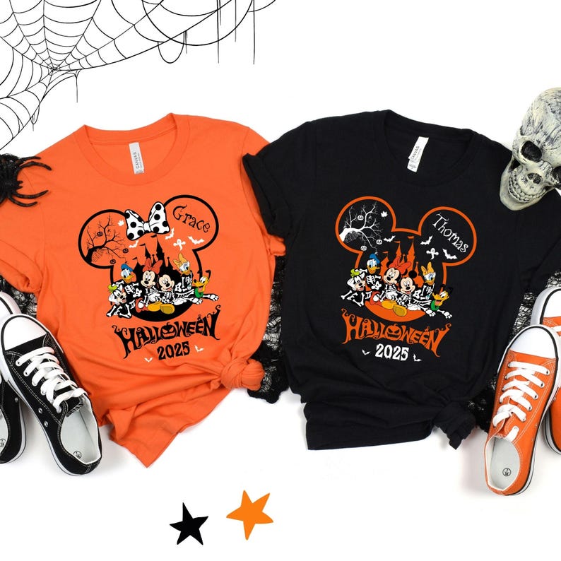 以下が含まれることがあります： ハロウィーンをテーマにしたTシャツ2枚。オレンジと黒で、ミッキーマウスのシルエットデザインが特徴です。オレンジのシャツには「Grace」という名前、黒のシャツには「Thomas」という名前が書かれています。どちらのシャツにもディズニーのキャラクターと「Halloween 2025」の文字が描かれています。