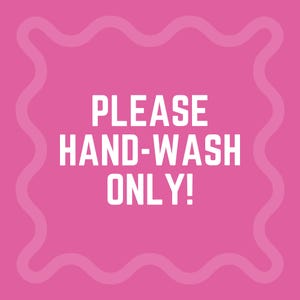 以下が含まれることがあります： 「PLEASE HAND-WASH ONLY！」という太字の白い文字が書かれた正方形のピンク色のサイン。サインには、波状の薄いピンク色のボーダーがあります。