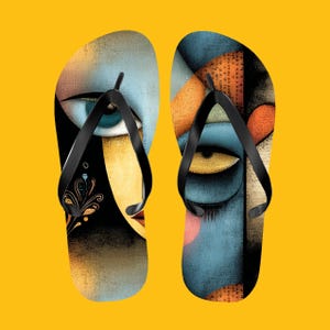 May include: A pair of flip-flops with a colorful abstract face design. The sandals feature black straps and a yellow background. The artwork includes blue, orange, and yellow hues, creating a unique and artistic look.