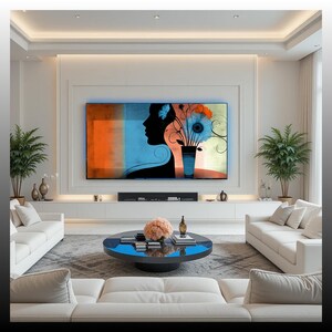 May include: A modern living room featuring a large abstract painting with a woman's silhouette and floral elements. The room includes white sofas, a blue coffee table, and potted plants, creating a contemporary and stylish interior design.