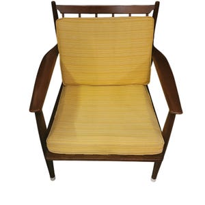 May include: A mid-century modern armchair with a dark wood frame and curved armrests. The seat and back cushions are yellow with a subtle striped pattern. The chair has a low profile and a minimalist design, perfect for a living room or lounge area.