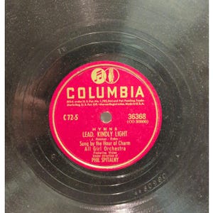 May include: Vintage Columbia Records 78 RPM vinyl record. The red label features the Columbia logo and text including "Lead, Kindly Light" and "All Girl Orchestra". The record is black with visible grooves.