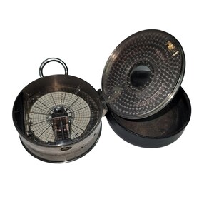 May include: A vintage silver-toned instrument with a circular dial and a hinged lid. The dial features a grid pattern and a central mechanism. The lid is open, revealing a textured surface. The instrument is housed in a black leather case.