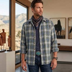 May include: A plaid button-down shirt in shades of blue, green, and white, paired with a dark blue shirt and jeans. The outfit is accessorized with a patterned neckerchief and a turquoise belt buckle. A watch is visible on the wrist.