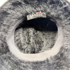 K&ouml;nnte beinhalten: Eine wei&szlig;e Keramik-Tasse mit schwarzem Henkel und dem Text "But First, Coffee" in schwarzer, handschriftlicher Schrift. Die Tasse steht auf einer wei&szlig;en Oberfl&auml;che.