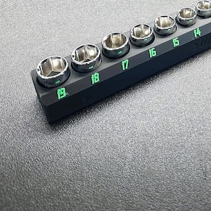 Puede incluir: Un organizador de zócalos negro con números verdes del 7 al 19. El organizador está lleno de zócalos de varios tamaños.