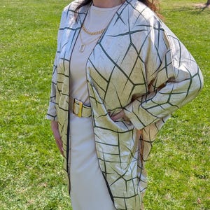 May include: A beige kimono with a geometric pattern in green. The kimono has a long, flowing silhouette and is made of a soft, silky fabric.