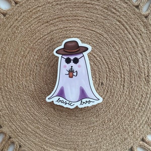 May include: A purple ghost wearing a brown hat and sunglasses, holding a cup of coffee. The ghost has the text "basic boo" written below it.