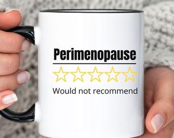May include: White ceramic mug with a black handle and rim. The mug features the text "Perimenopause" above a row of four yellow star ratings and the phrase "Would not recommend".