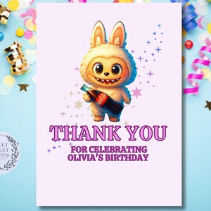 May include: A birthday thank you card featuring a cartoon bunny holding a Coca-Cola bottle. The card has the text "THANK YOU FOR CELEBRATING OLIVIA'S BIRTHDAY" in purple. The background is light pink with star accents.