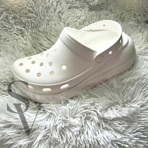May include: White platform clog shoe with a textured sole and a strap across the top.