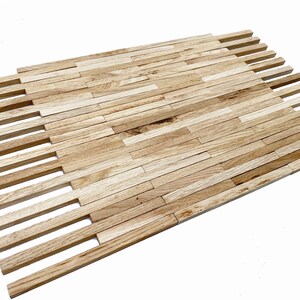 May include: A close-up of a wooden tile mosaic made of thin, rectangular pieces of wood arranged in a staggered pattern. The wood is a light brown color with a natural grain.