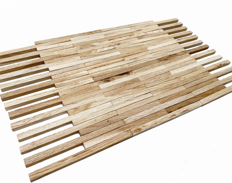 May include: A close-up of a wooden tile mosaic made of thin, rectangular pieces of wood arranged in a staggered pattern. The wood is a light brown color with a natural grain.