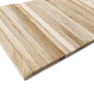 May include: A close-up of a wooden panel made of thin, light brown wood strips arranged horizontally. The panel is angled to show the edges of the strips.