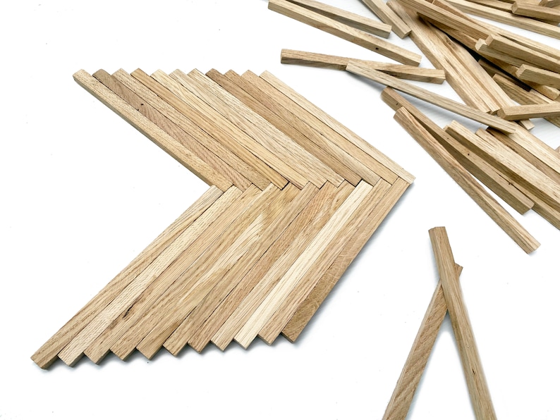 May include: A wooden arrow shape made from thin wooden strips. The arrow is made of natural wood with a light brown color. There are extra wooden strips scattered around the arrow.
