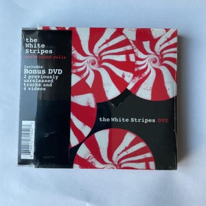 May include: A CD case with a red and white peppermint swirl design. The text "the White Stripes" and "white blood cells" is printed on the front. The case includes a bonus DVD with 2 previously unreleased tracks and 4 videos.
