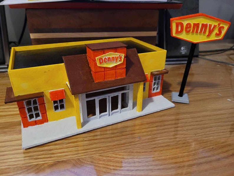 May include: A yellow and brown model of a Denny's restaurant with a red and yellow sign that reads "Denny's".
