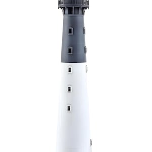 May include: A white and black lighthouse model with a black roof and a black lantern room. The lighthouse has a small door and a set of stairs leading up to the door.