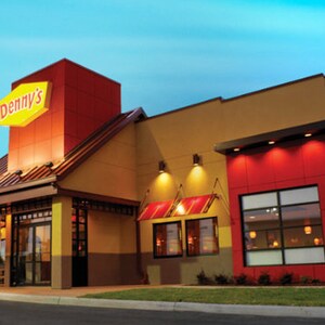 May include: Exterior view of a Denny's restaurant at dusk. The building is yellow with red accents and a large sign with the Denny's logo in red and yellow.