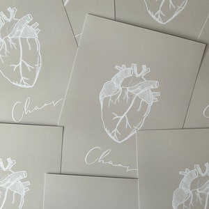 May include: A set of six beige cards with a white anatomical heart illustration and the word "Chaos" written in cursive on each card.