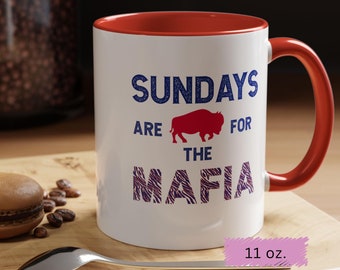 Op de afbeelding: Witte keramische mok met een rode binnenkant en oor. De mok heeft de tekst "SUNDAYS ARE FOR THE MAFIA" in blauw en paars, met een rode buffelafbeelding. De mok bevat ongeveer 325 ml.