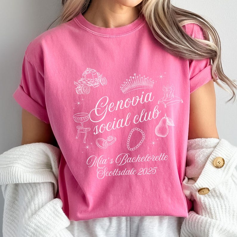 May include: Pink t-shirt with white graphic text and illustrations. The text reads "Genovia social club" with "Mia's Bachelorette Scottsdale 2025" below. Illustrations include a crown, carriage, and jewelry.