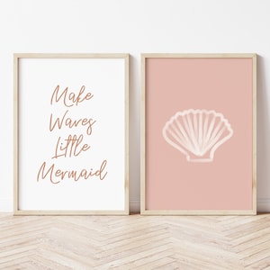 May include: Two framed prints with a beach theme. The left print has the text "Make Waves Little Mermaid" in brown script. The right print has a white seashell on a pink background.