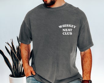 May include: A dark gray t-shirt with the text "Whiskey Neat Club" printed in white on the front.