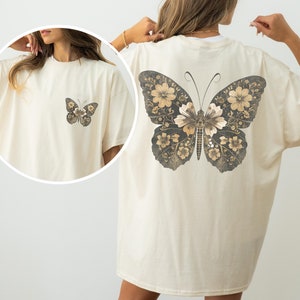 Vintage-style butterfly Comfort Colors t-shirt featuring a small floral butterfly graphic on the front and a large, detailed botanical butterfly on the back. Soft oversized aesthetic, perfect for cottagecore outfits, nature lovers, and retro graphic tee fans.