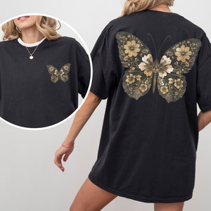 Pu&ograve; includere: Maglietta nera oversize con un design a farfalla dorata sul retro. La farfalla &egrave; composta da dettagli floreali.