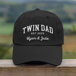 May include: Black baseball cap with white embroidered text that reads "Twin Dad Est 2025 Ryan & Julie".