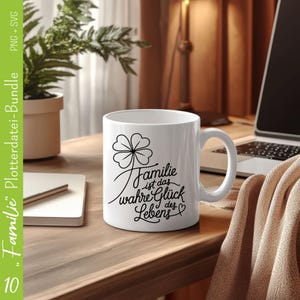 May include: White ceramic mug with a black clover design and the text "Familie ist das wahre Gl&uuml;ck des Lebens" in a cursive font.
